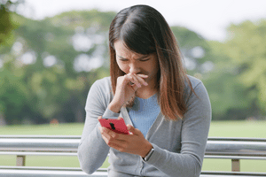 Image of woman upset by online harassment on her mobile phone