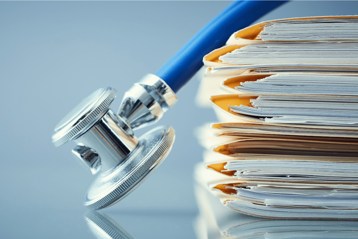 Stack of medical records with a stethoscope draped on top. Learn about the medical record retrieval process from Bosco Legal Services.