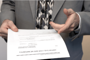 A man in a grey suit holding a court subpoena document for review.